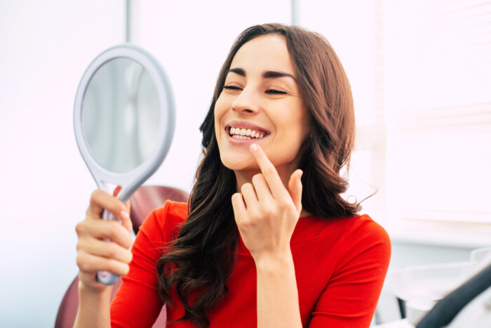smile makeover, woman looking at smile transformation in mirror